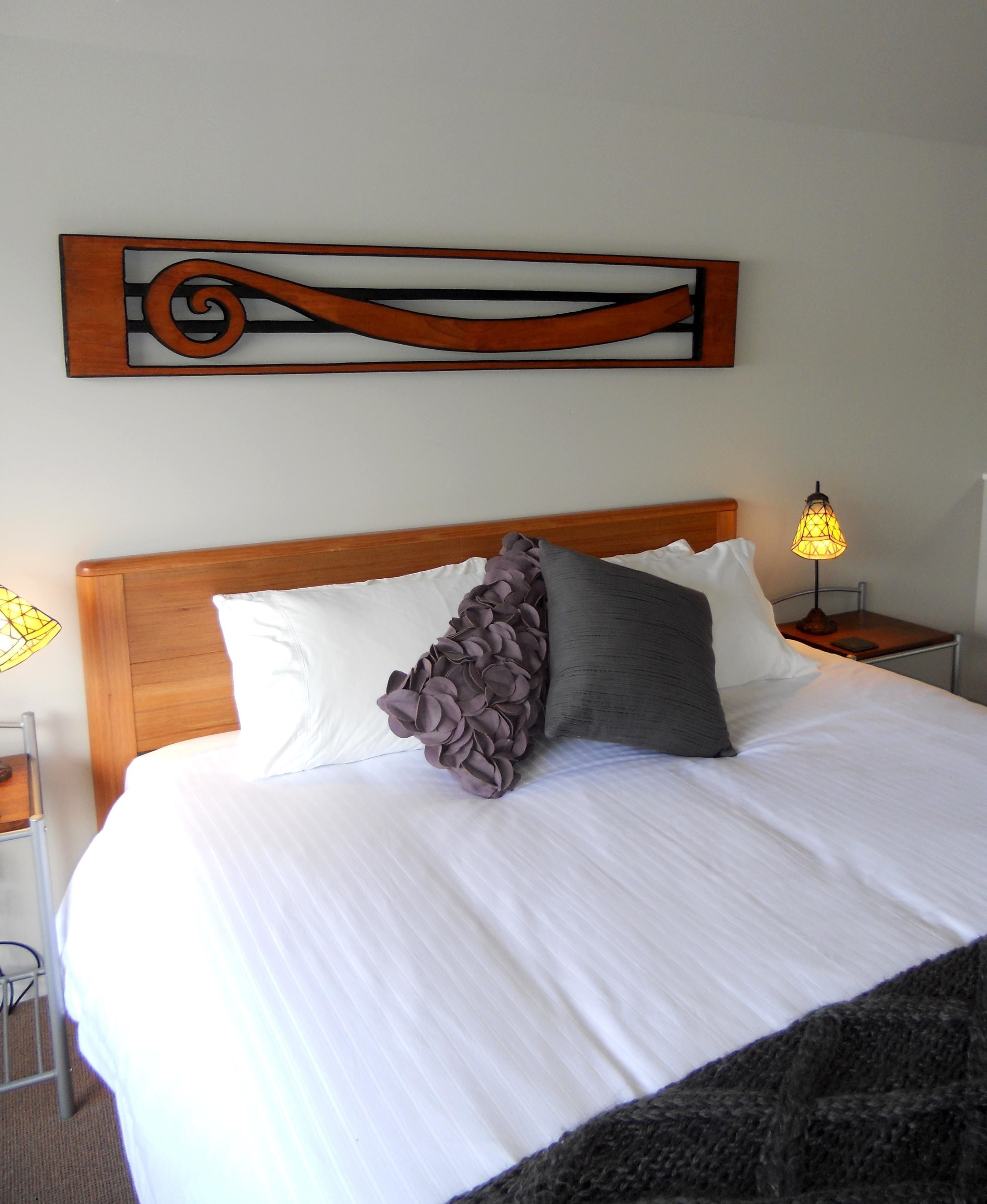 A neatly made bed with white linens and two pillows, one with a ruffled design.