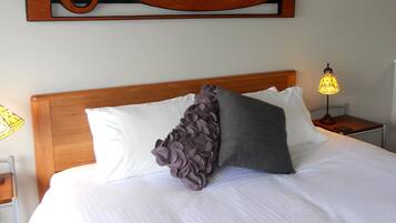 A neatly made bed with white linens and two pillows, one with a ruffled design.