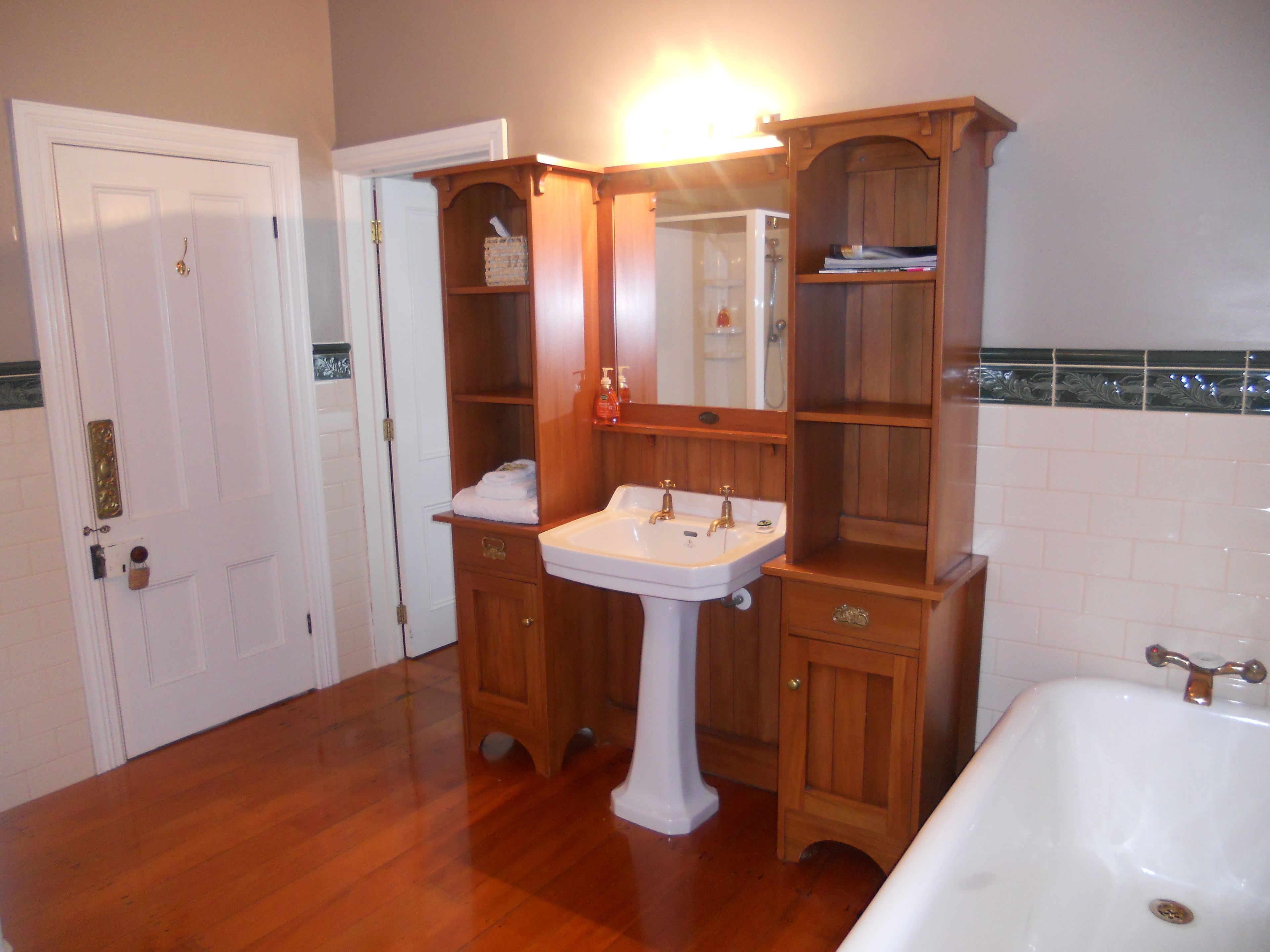Un baño con tocador de madera, lavamanos pedestal y bañera.