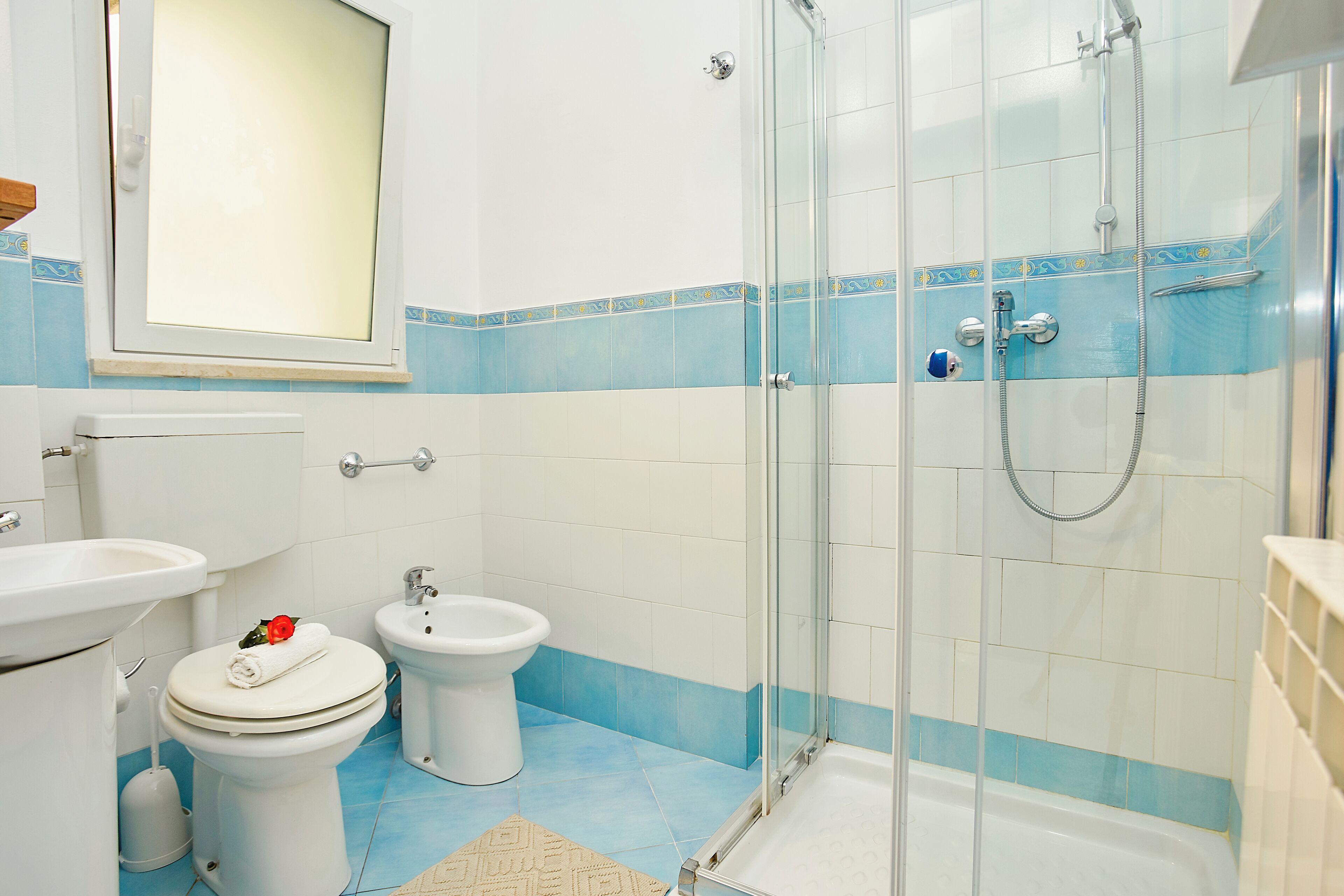 A bathroom with a glass-enclosed shower, a toilet, a bidet, and a sink.