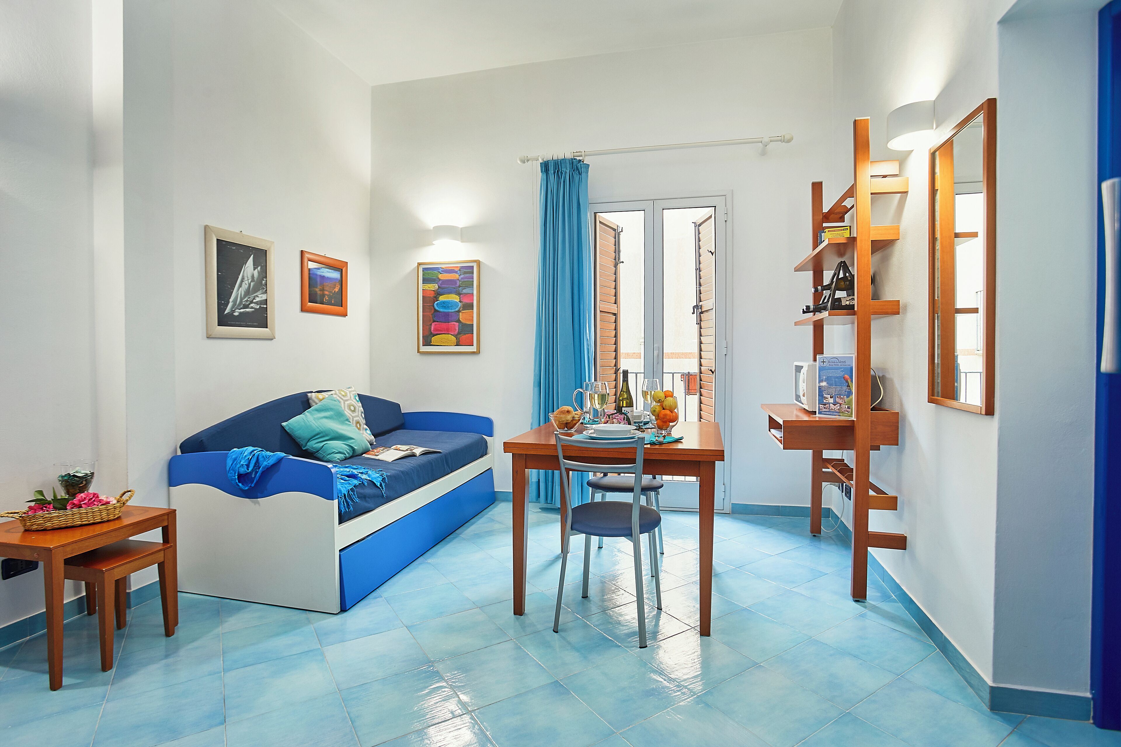A compact living space with a sofa, a dining table, and a small kitchen area.