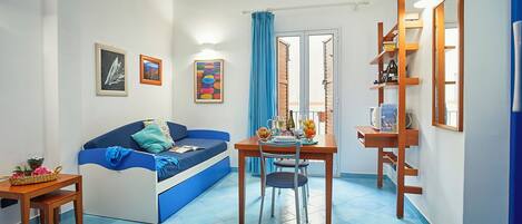 A compact living space with a sofa, a dining table, and a small kitchen area.