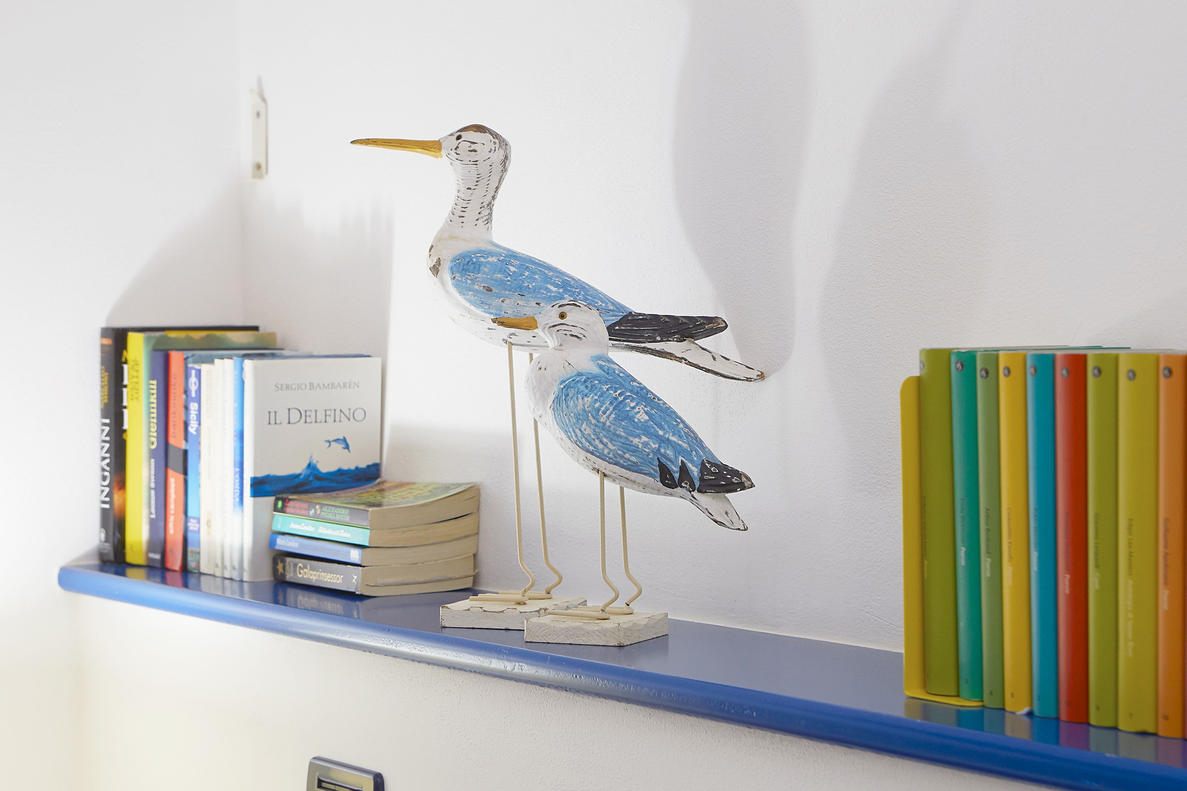 Una estanteria amb llibres i una escultura d'ocell.