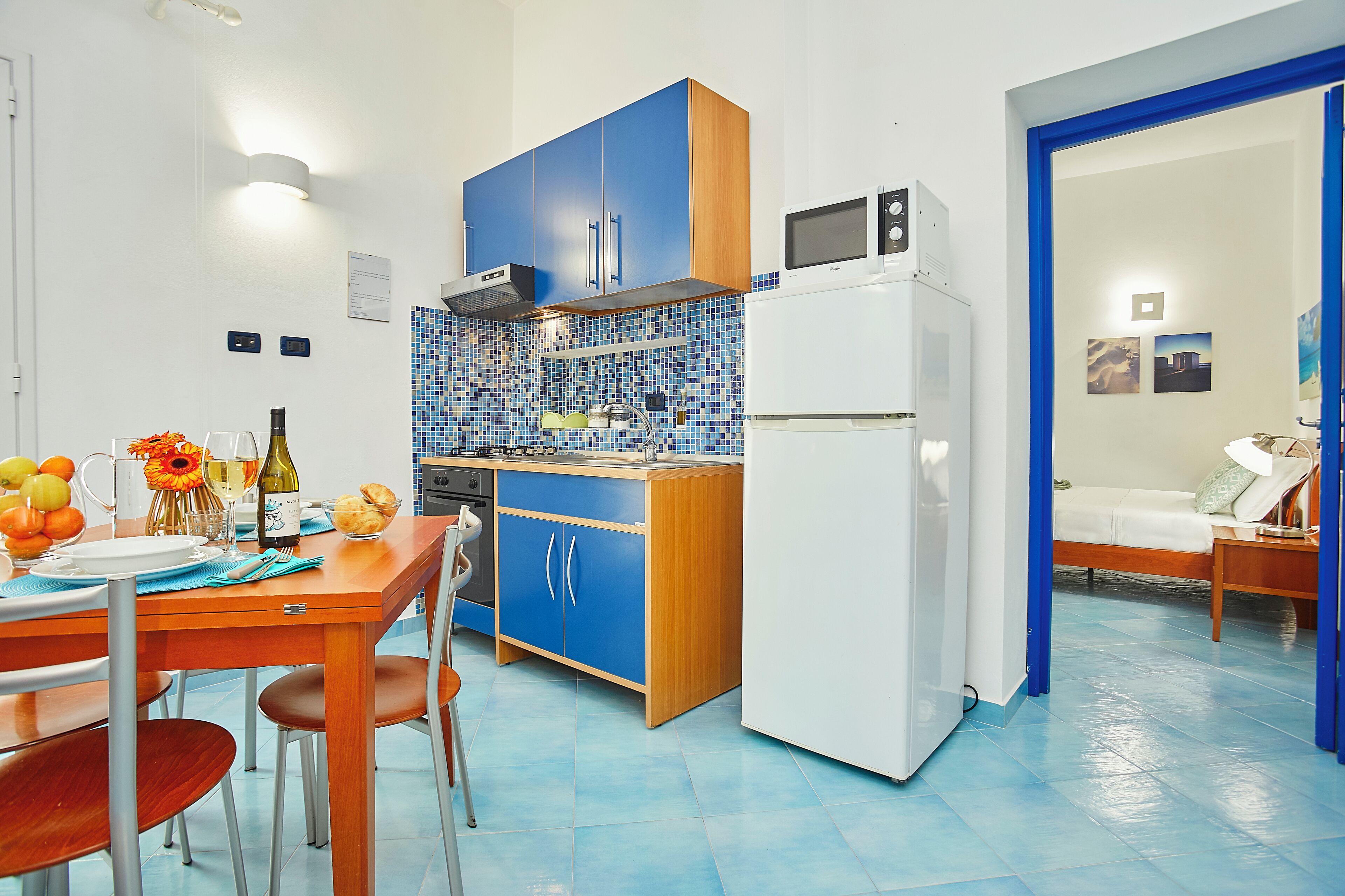 Een moderne keuken met blauwe kastjes, een witte koelkast en een betegelde achterwand.