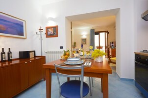A dining area with a wooden table, chairs, and a kitchen in the background.