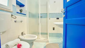 A bathroom with a toilet, bidet, and a glass-enclosed shower.
