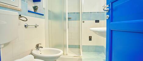A bathroom with a toilet, bidet, and a glass-enclosed shower.
