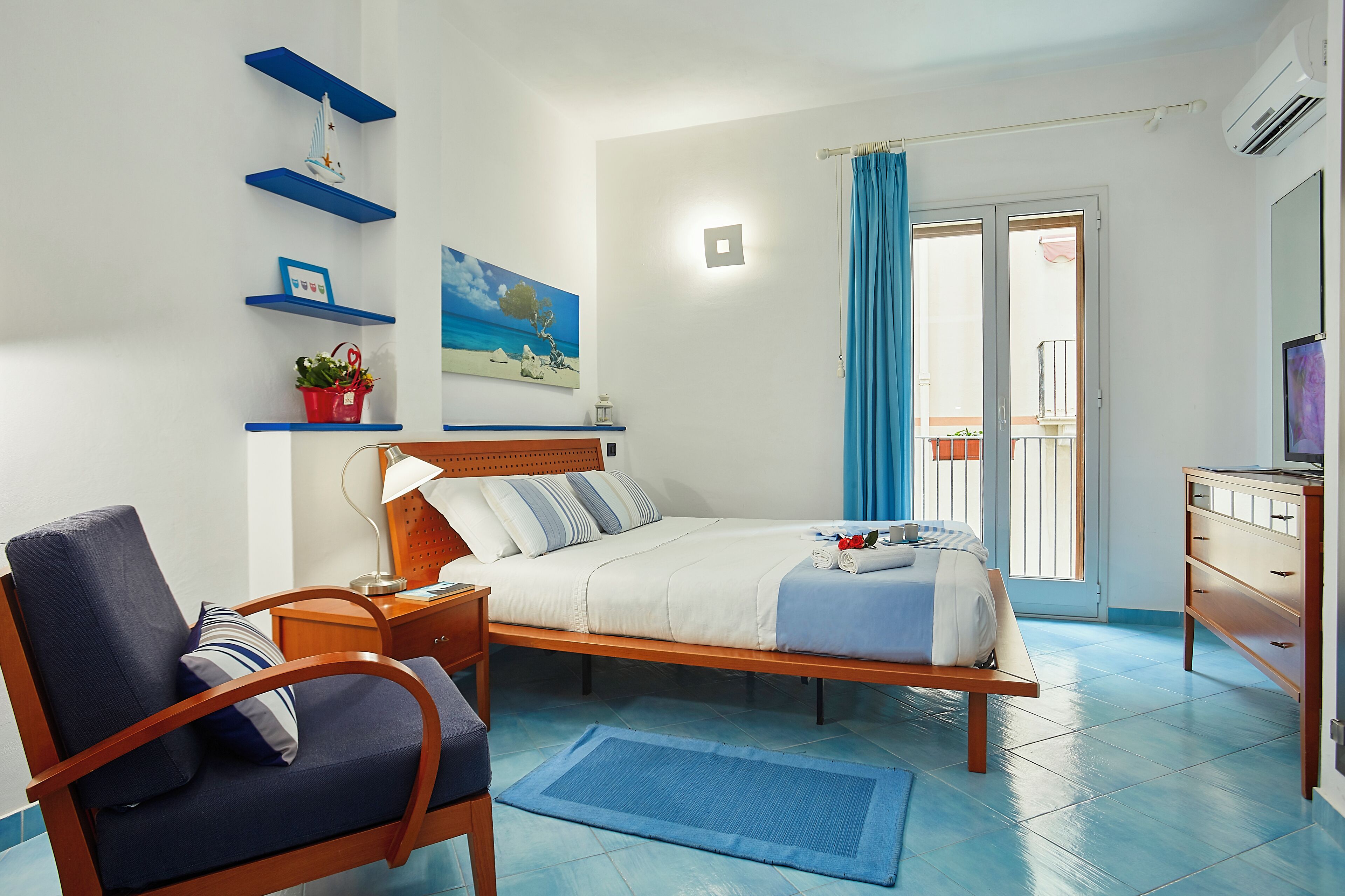 A bedroom with a bed, a chair, a nightstand, a dresser, and a window with curtains.