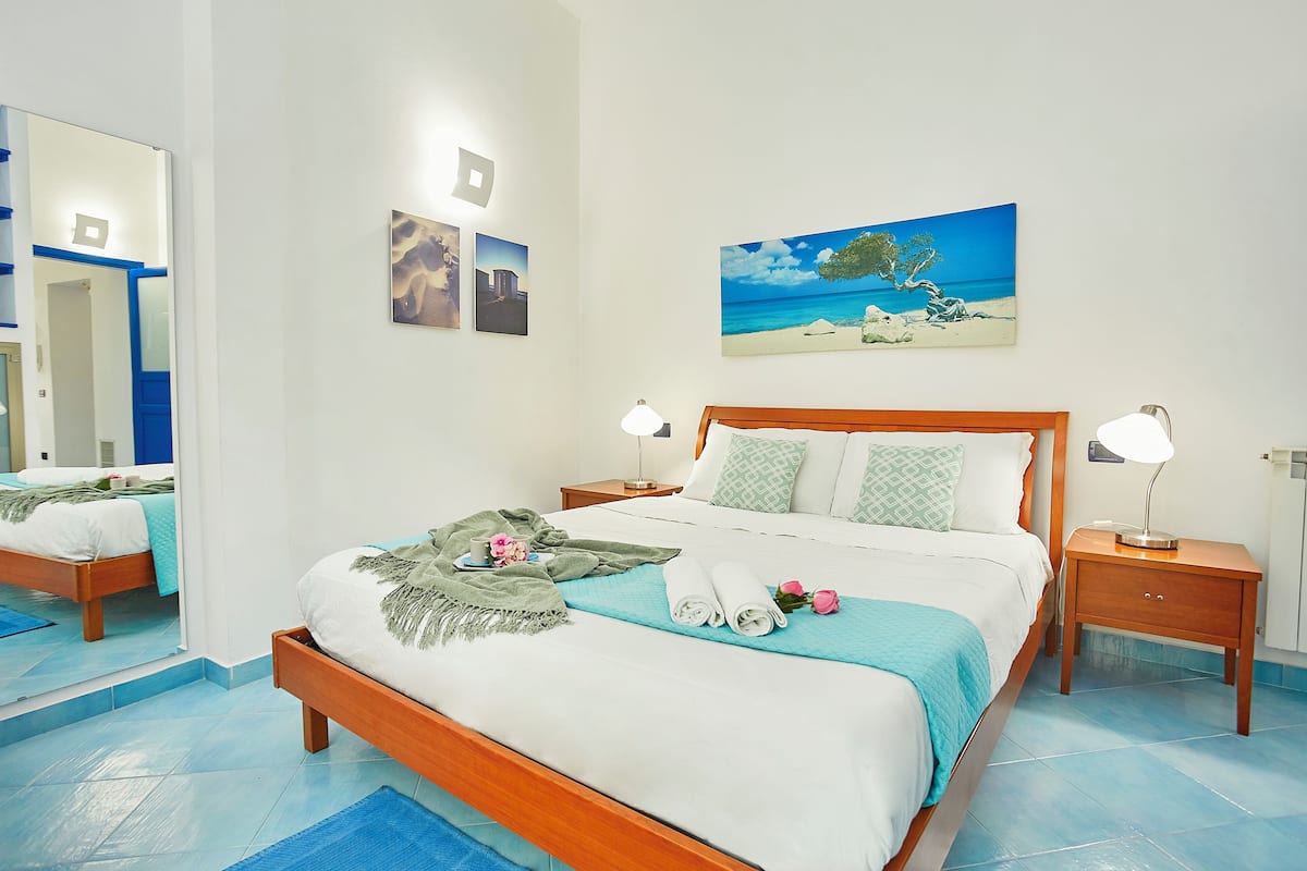 A neatly made bed with a blue bedspread, a wooden headboard, and two bedside lamps.