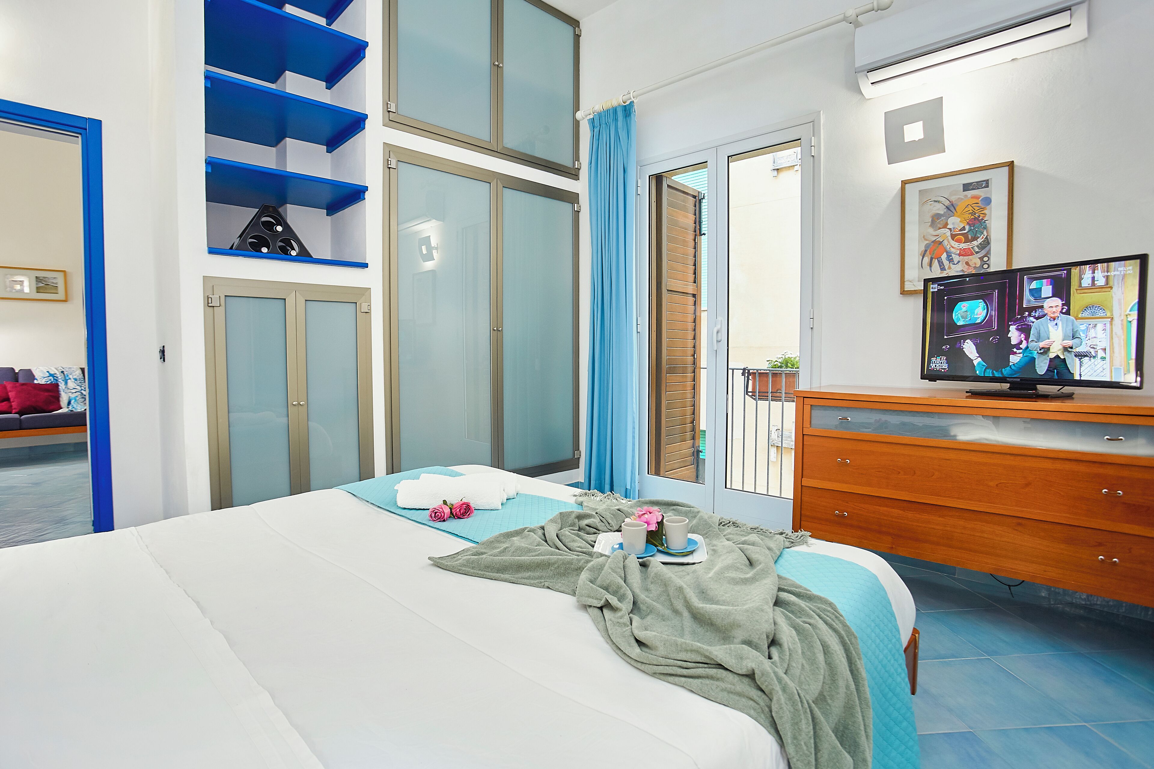 A hotel room with a bed, a wooden dresser, a TV, and a bathroom with a shower and a toilet.