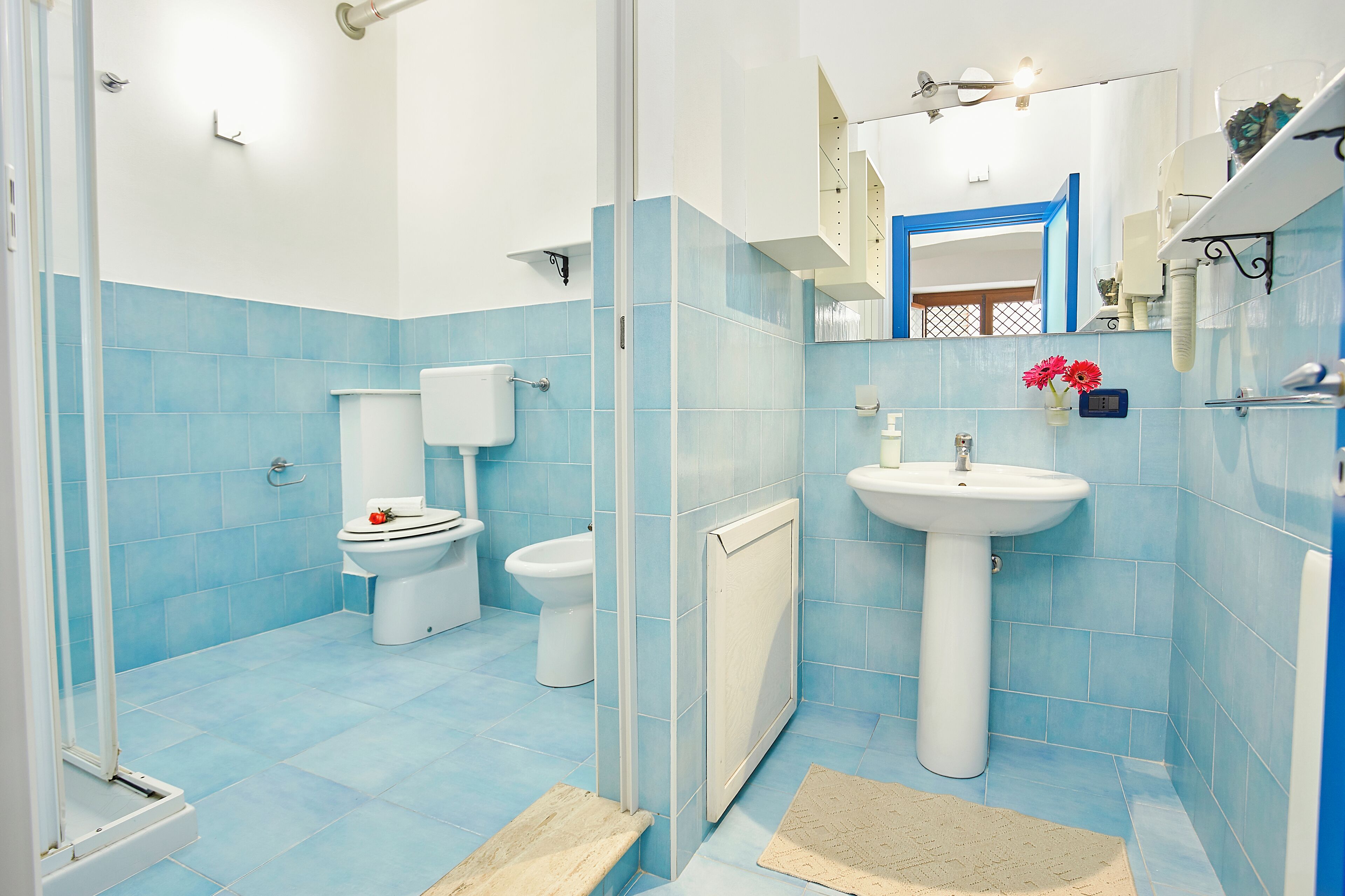 Un bagno con piastrelle blu, un lavandino bianco e un water.