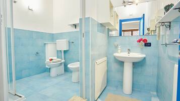 Un bagno con piastrelle blu, un lavandino bianco e un water.