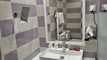 A modern bathroom with a white sink, a mirror, and a shower area.