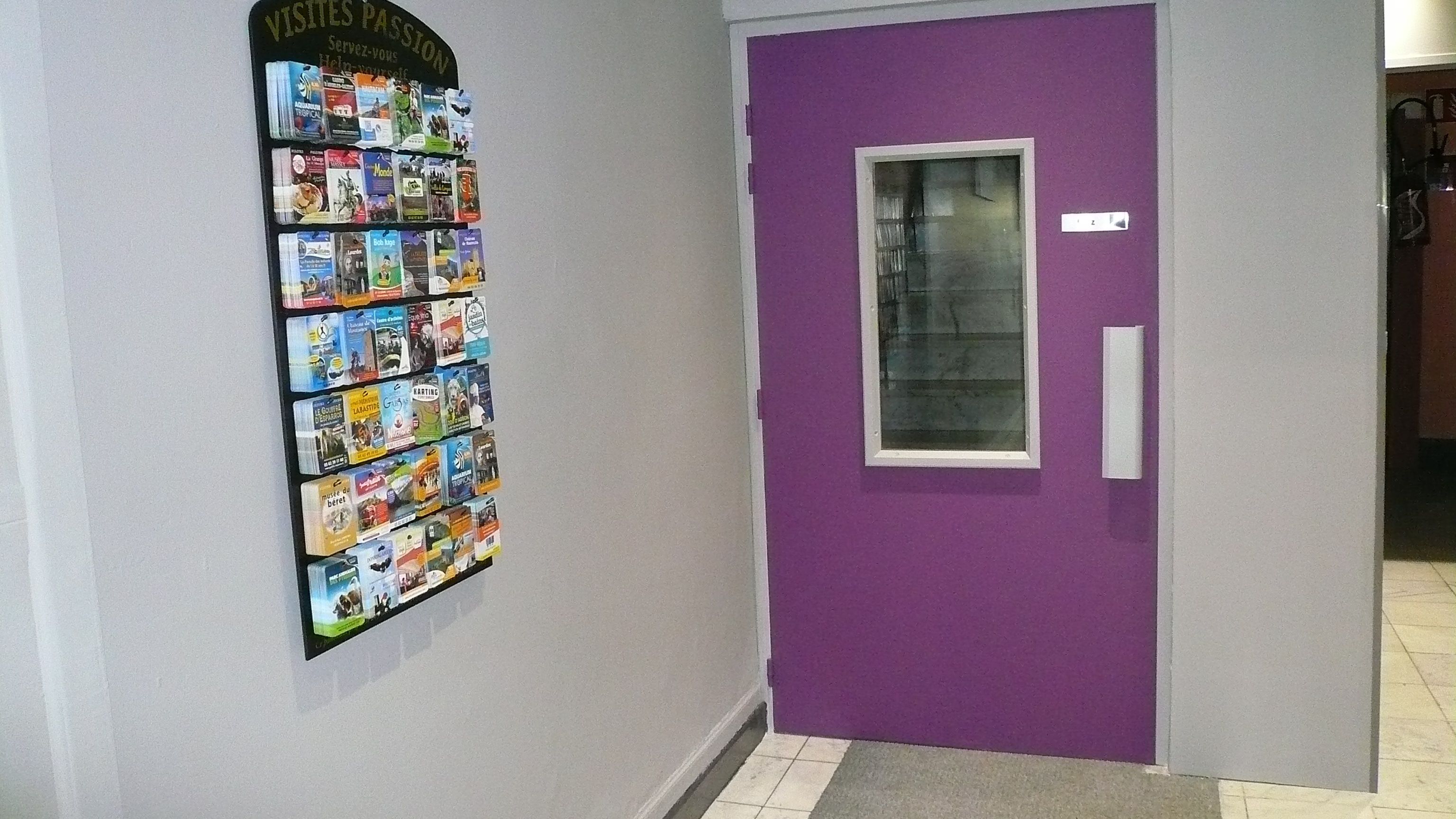 Un pasillo con una puerta morada y un tablón de anuncios mostrando varios libros.
