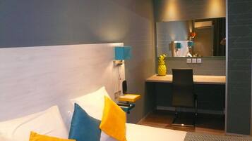 A modern hotel room with a bed, a desk, and a chair.