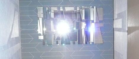 Un pasillo con pared de diseño azul, suelo de madera y una lámpara en el techo.