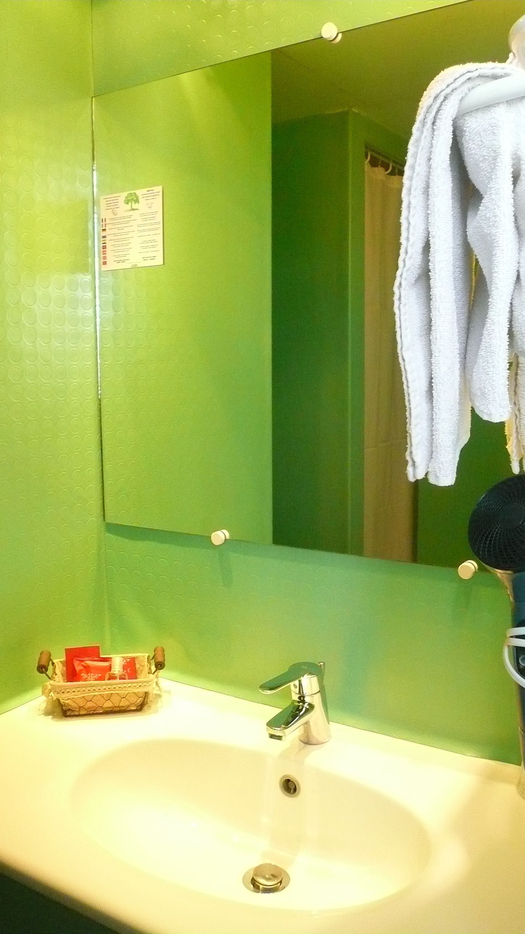 A bathroom with a green wall, a white sink, and a mirror.