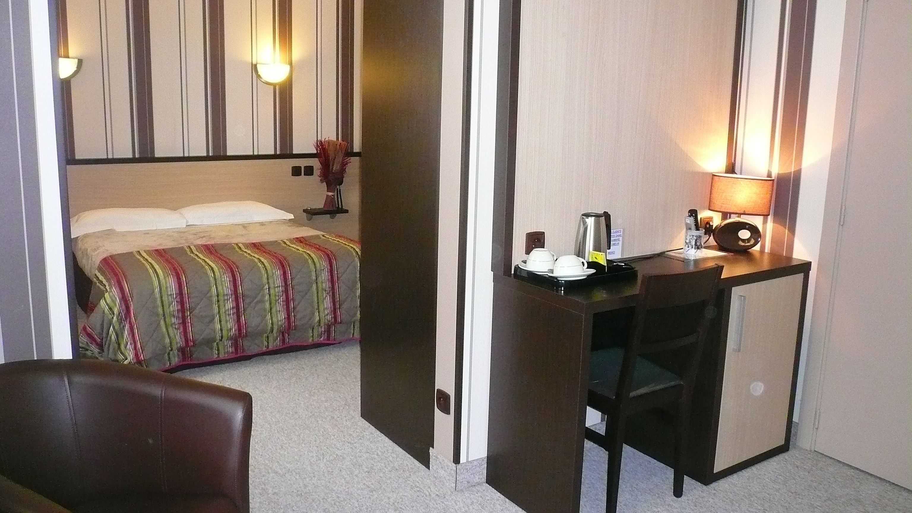 Une chambre d’hôtel avec un lit, un bureau doté d’une lampe et une chaise.