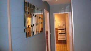 A hallway with a modern wall design, a mirrored wall, and a door leading to a bathroom with a towel rack. - Hôtel L'Européen (Tarbes)