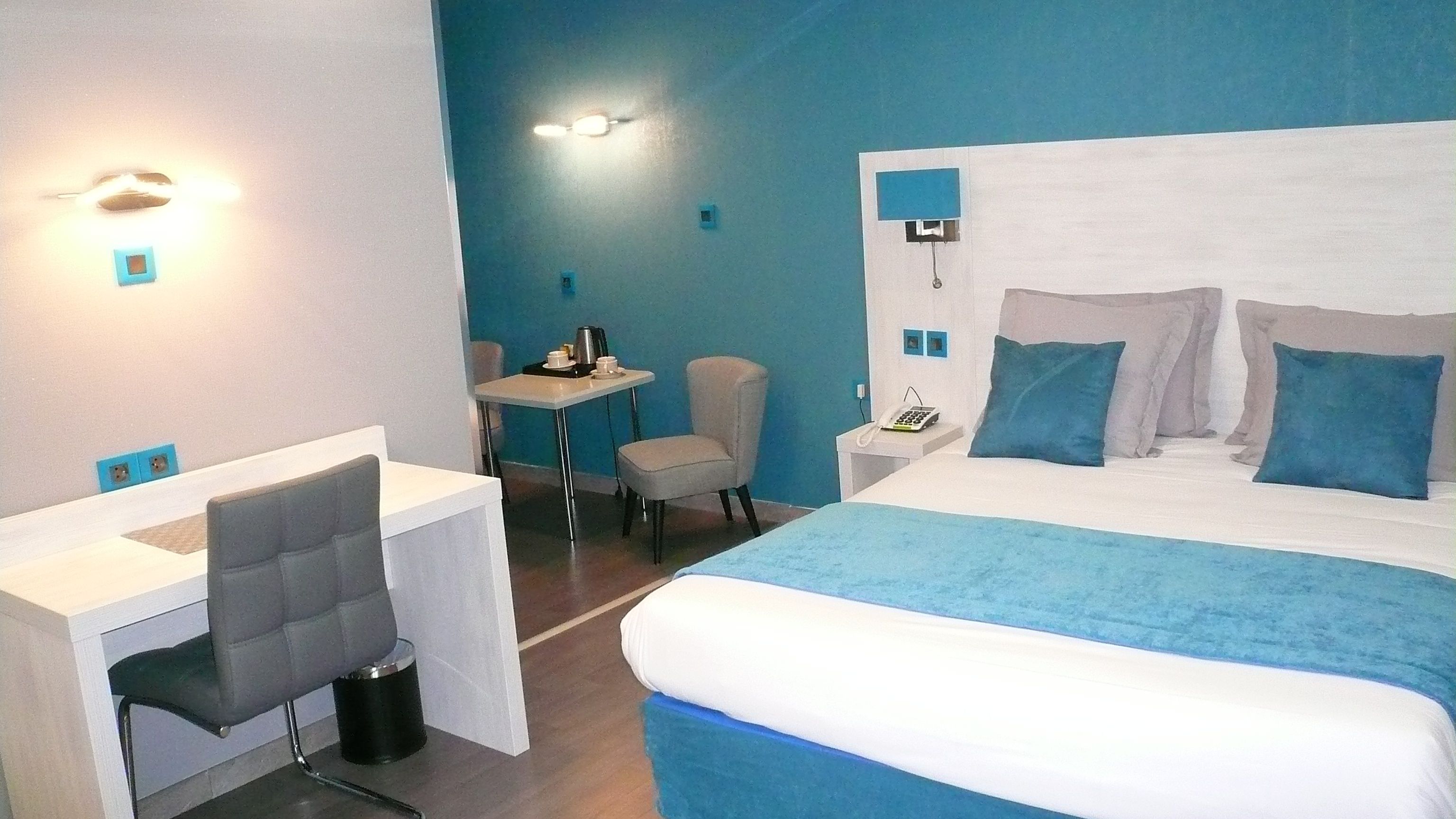 A hotel room with a bed, a desk, and a chair.