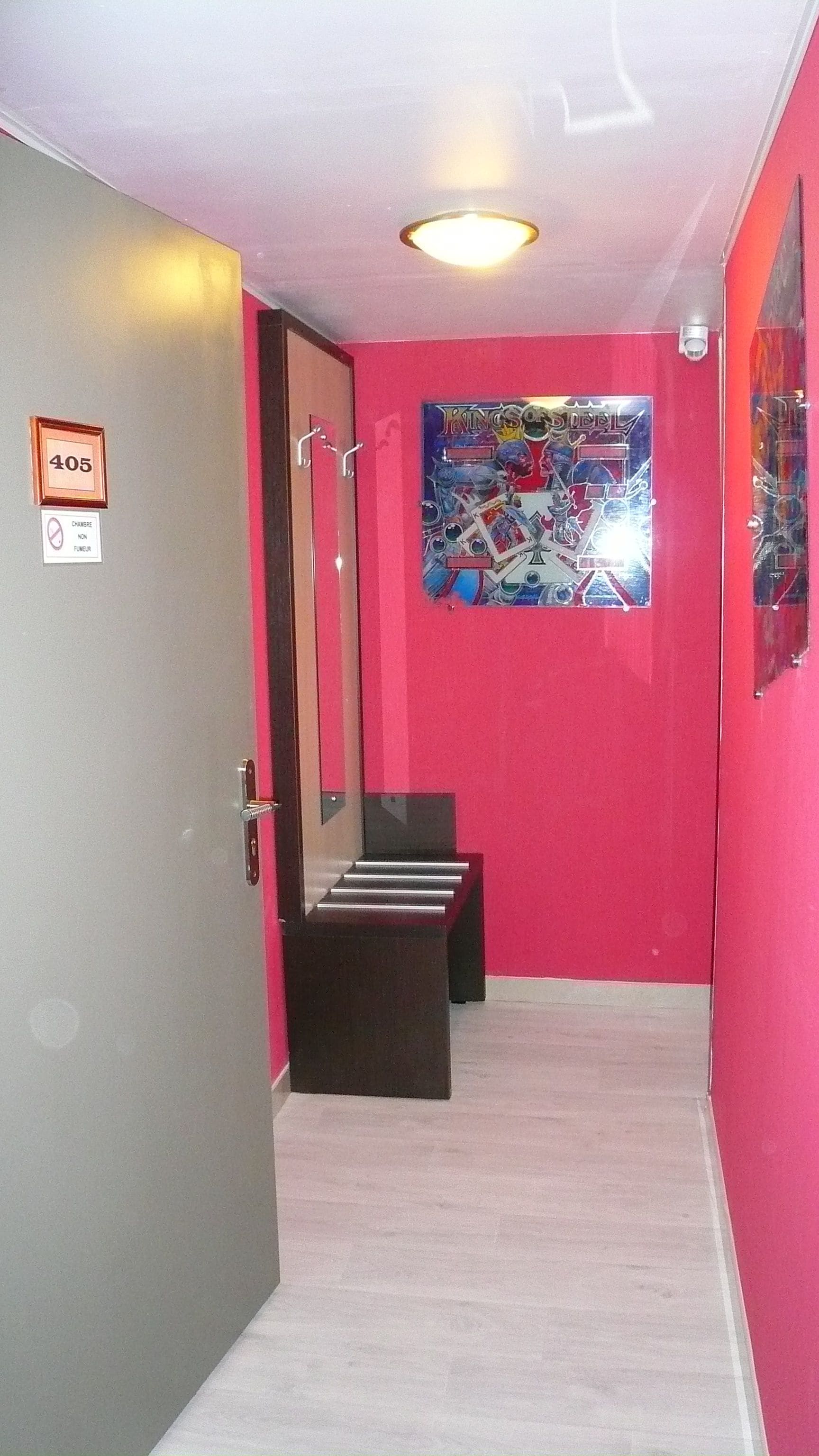 Un pasillo con una pared roja, una puerta con la etiqueta '405' y un cartel en la pared.