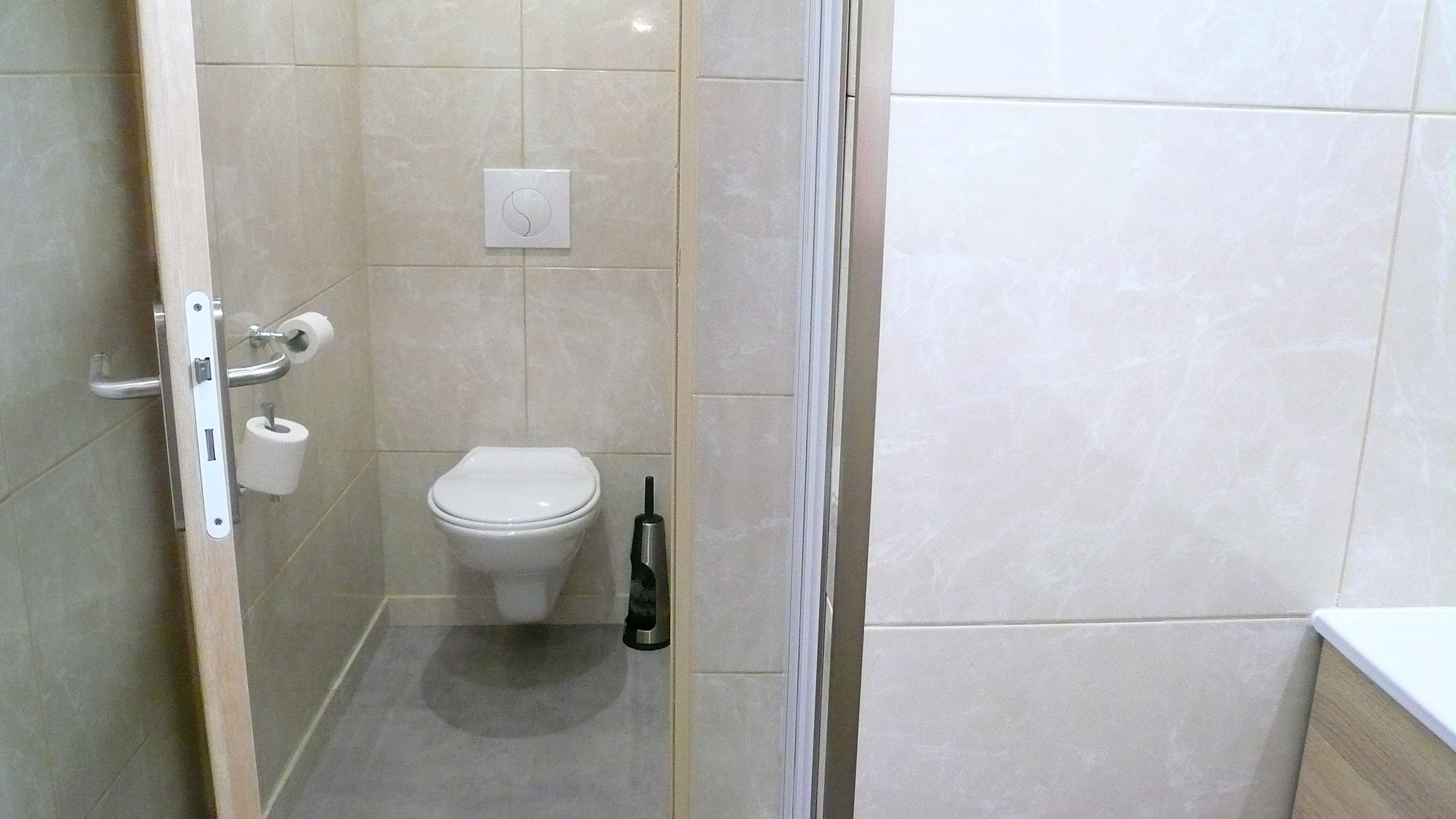 Une salle de bain équipée de toilettes, d’un sèche-mains et d’un porte-rouleau de papier toilette.