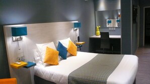 A modern hotel room with a large bed, two bedside tables, a desk, and a mirror. - Hôtel L'Européen (Tarbes)