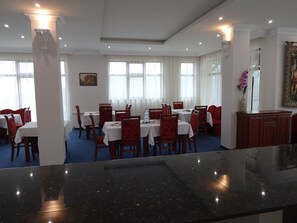 A dining area with tables and chairs, a marble counter, and a painting on the wall. - Pinerose Resort (Bansko)
