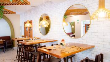 A restaurant interior with wooden tables, chairs, and hanging pendant lights.