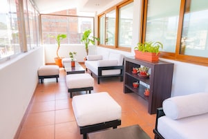A balcony with a sofa, ottoman, and potted plants.
