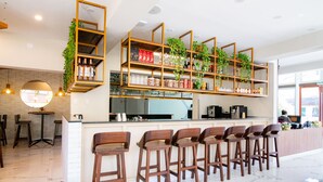 A modern bar area with wooden bar stools, a counter, and shelves with plants and bottles. - El Tumi (Huaraz)