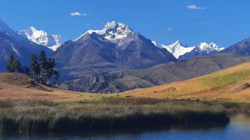 A mountain landscape with a clear sky, a body of water, and a grassy area.