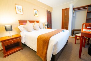 A hotel room with a bed, bedside table, lamp, and a wooden chair. - El Tumi (Huaraz)