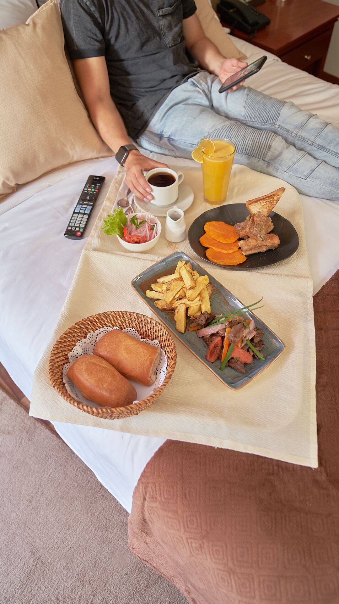 Un lit avec un plateau contenant divers éléments pour le petit-déjeuner, notamment des toasts, des frites et un sandwich.