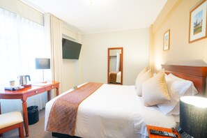 A hotel room with a bed, a desk, a chair, a TV, and a lamp. - El Tumi (Huaraz)