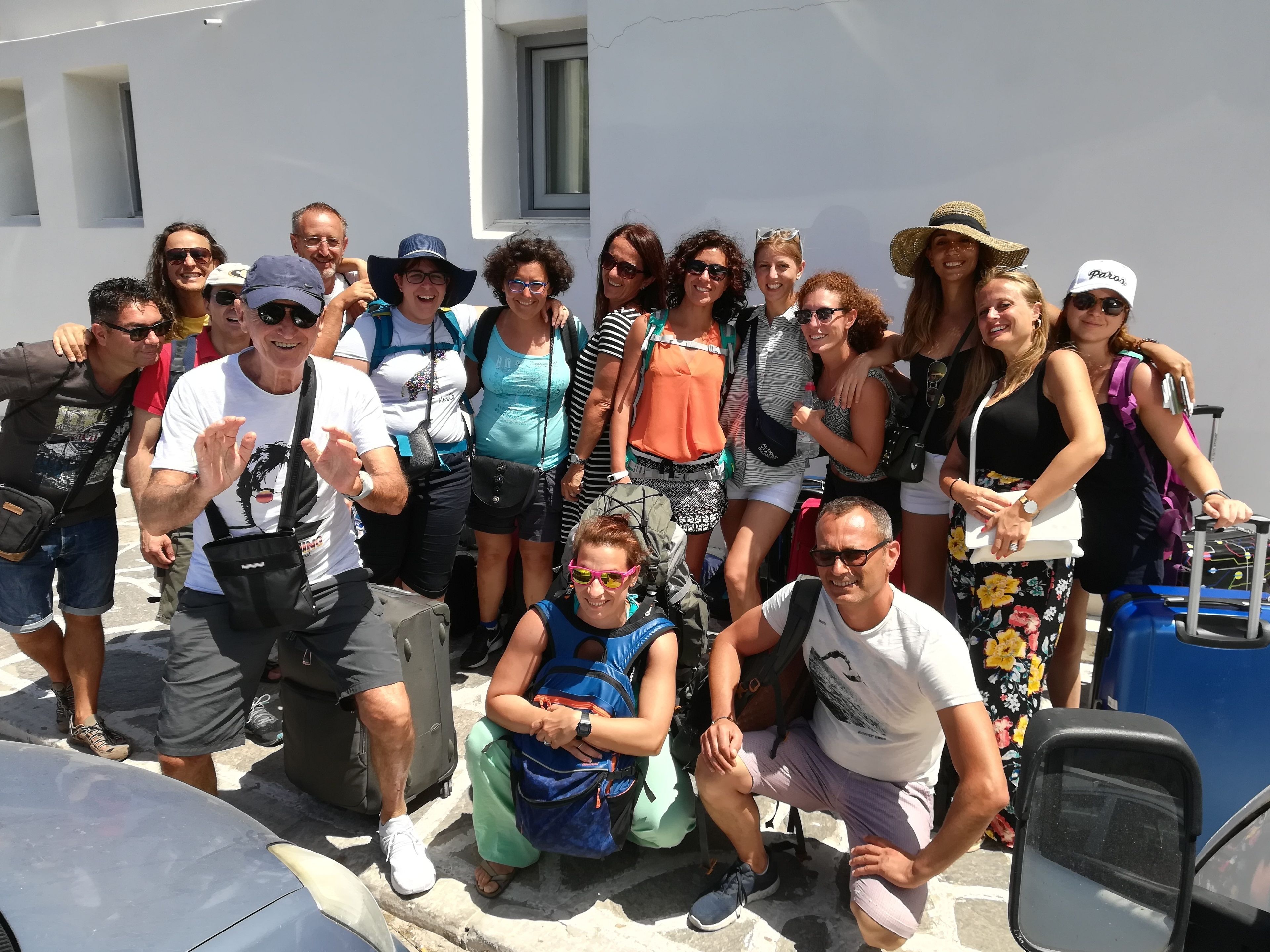 A group of people standing in front of a building with a white facade and a window.