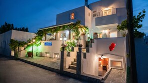 A modern building with a staircase leading to the entrance, potted plants, and a sign indicating it is an apartment complex. - Kontaratos Studios & Apartments (Paros)