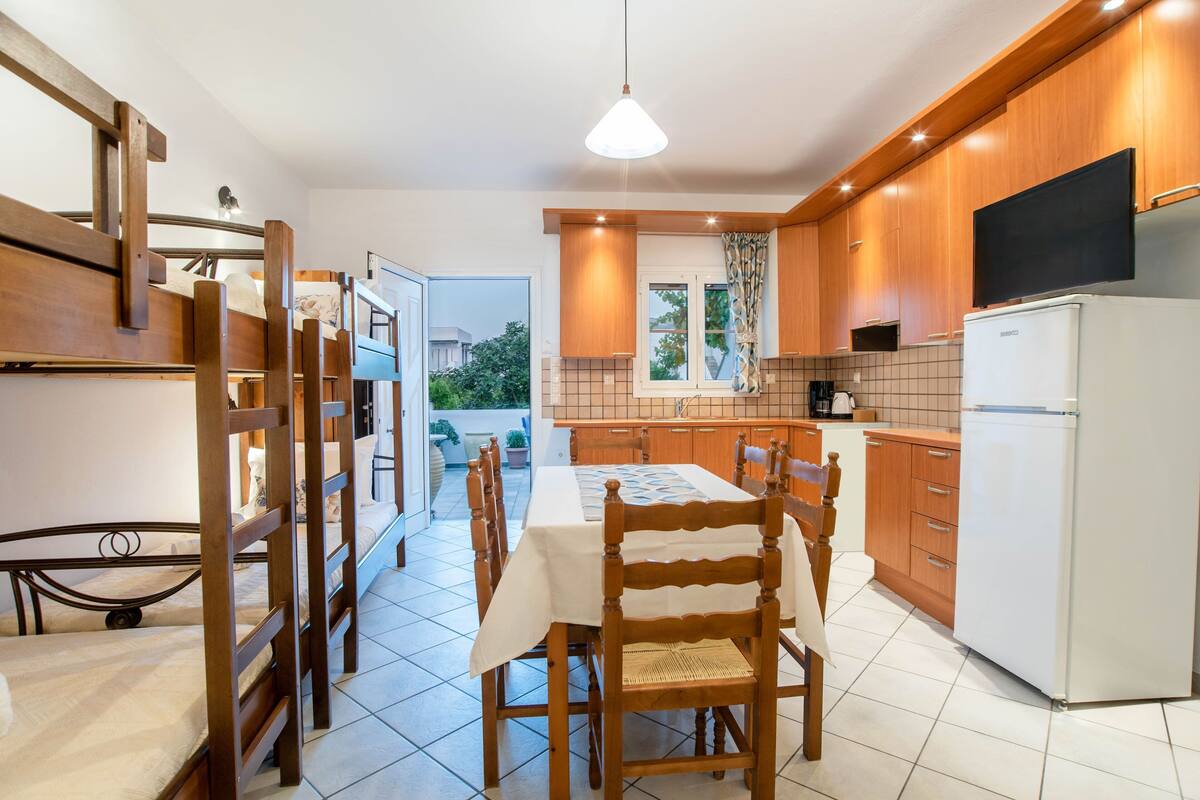A compact kitchen with wooden cabinets, a dining table, and a refrigerator.
