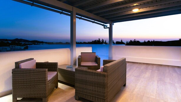 An outdoor seating area with wicker furniture and a view of the landscape. - Kontaratos Studios & Apartments (Paros)