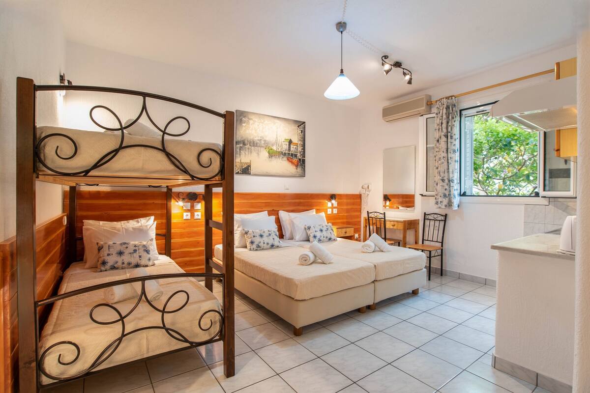 A room with a bunk bed, a sofa bed, a desk, and a chair.