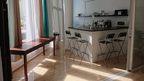 A modern kitchen with a bar area, a dining table, and chairs. - Hotel Manantiales (Torremolinos)