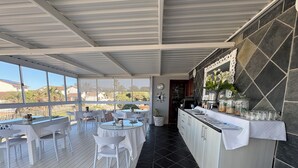 A restaurant with outdoor seating, a kitchen area, and a view of the surrounding landscape. - Le Blue Guesthouse (Gqeberha (Port Elizabeth))