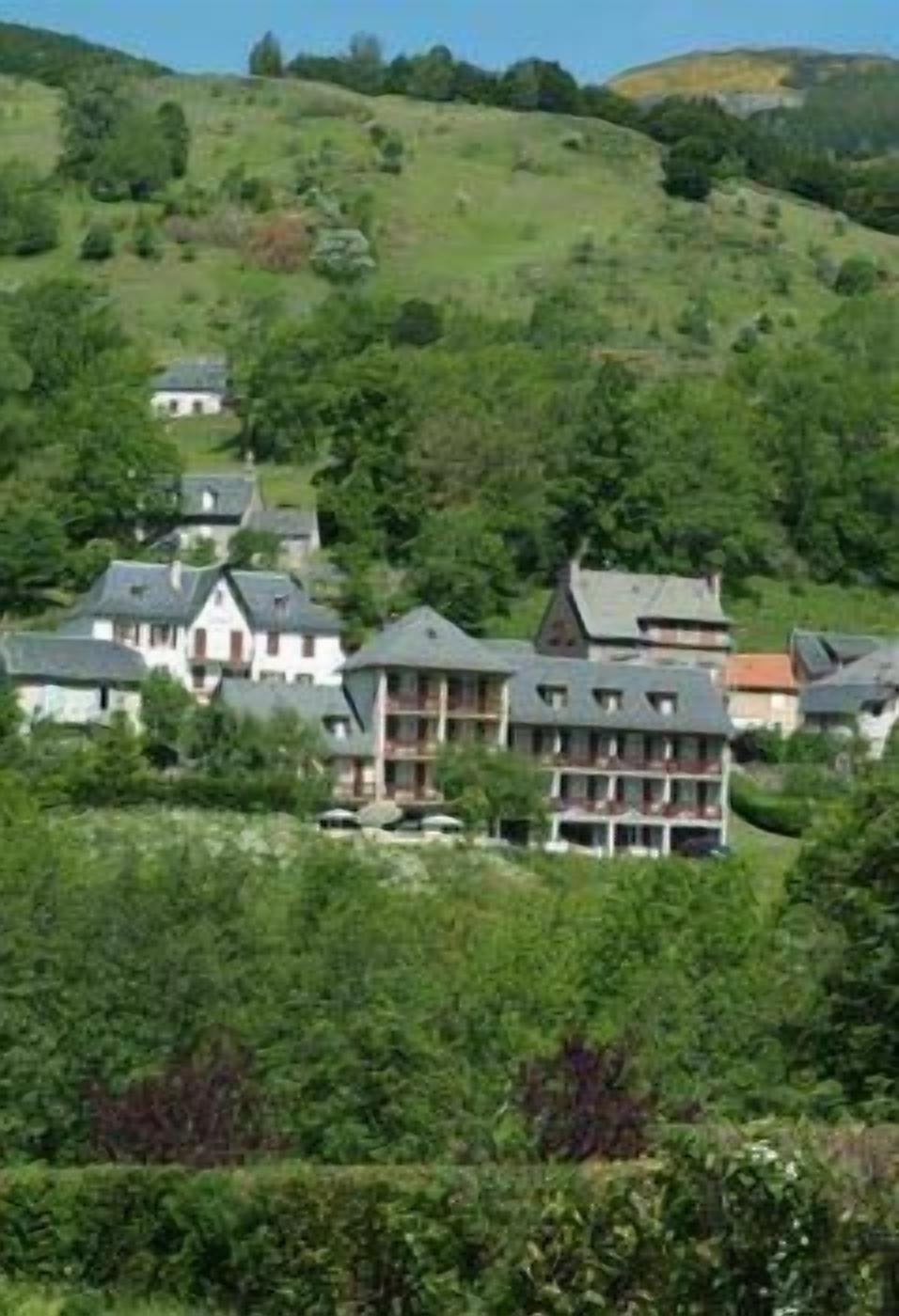 Une propriété située sur une colline, comprenant plusieurs bâtiments, probablement un complexe hôtelier ou un hôtel, et entourée d’une végétation luxuriante.