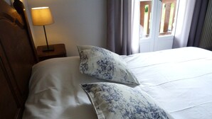Una cama con ropa blanca y dos almohadas decorativas con un estampado azul.