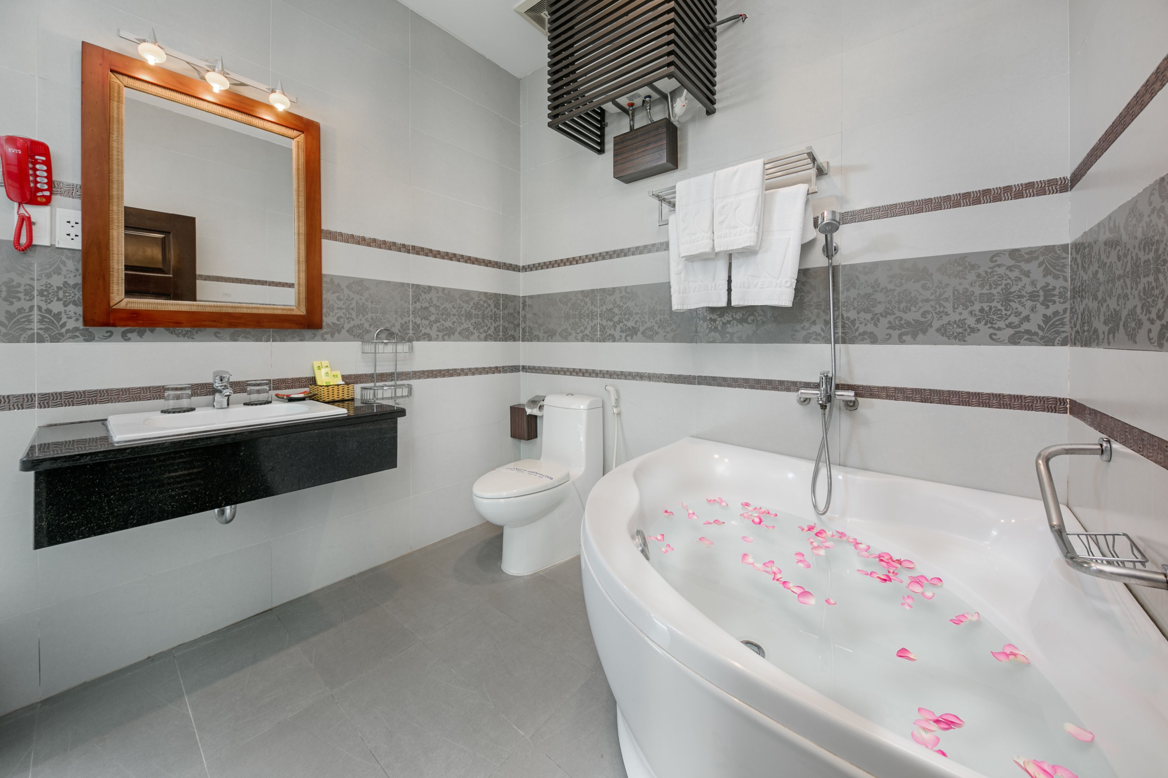 A modern bathroom with a large bathtub, a toilet, a sink, and a mirror.