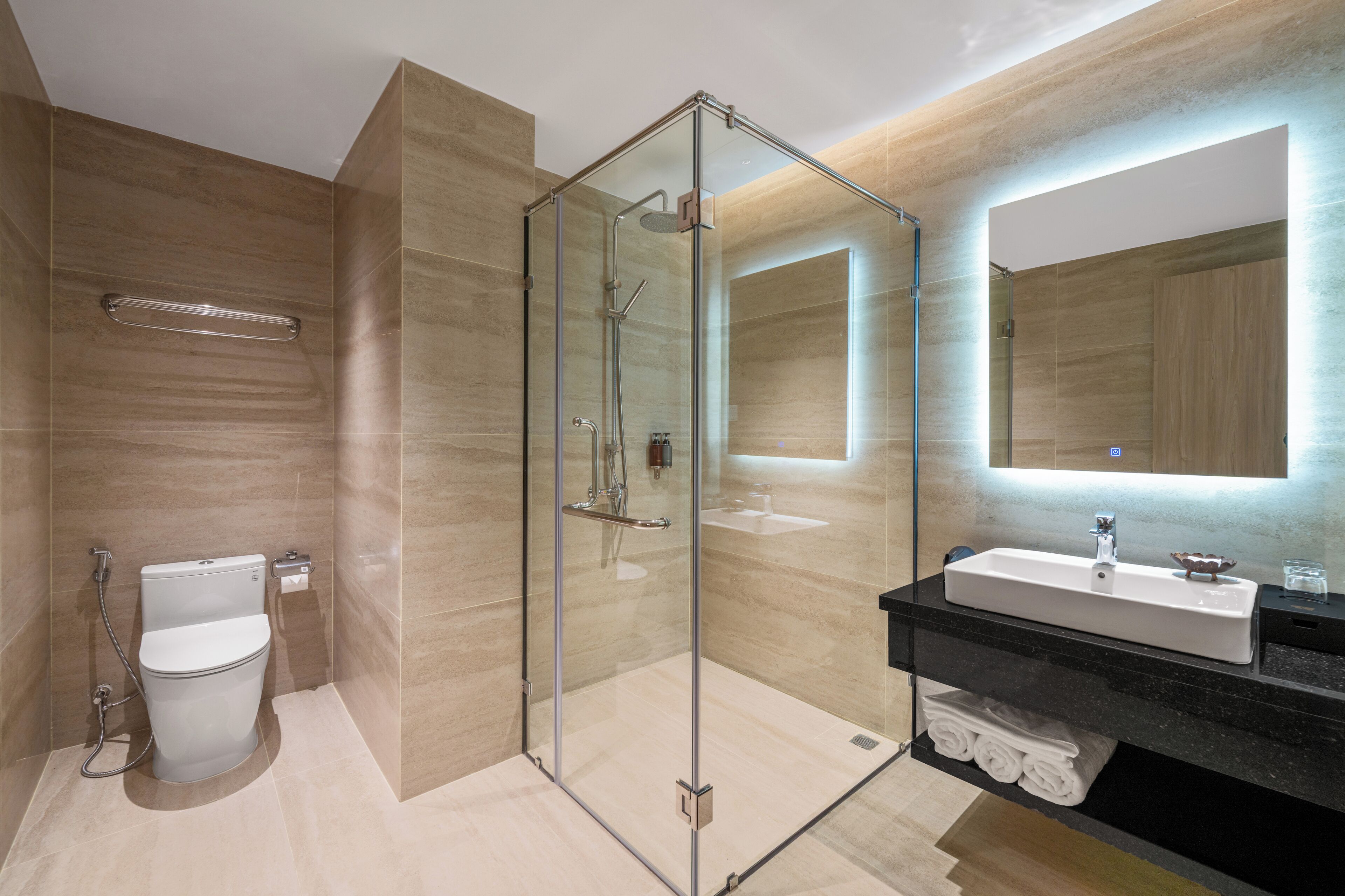 A modern bathroom with a glass-enclosed shower, a white toilet, a black vanity with a sink, and a mirror.