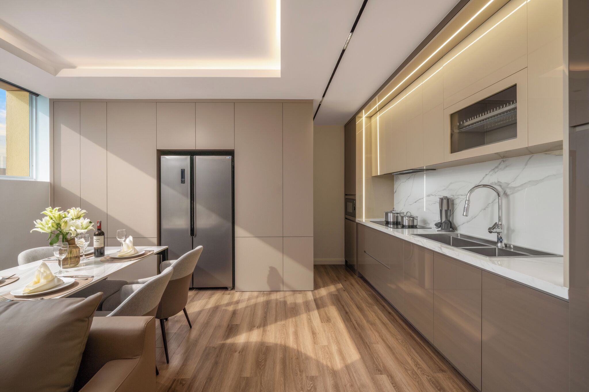 A modern kitchen with a built-in refrigerator, a marble countertop, and a sleek faucet.