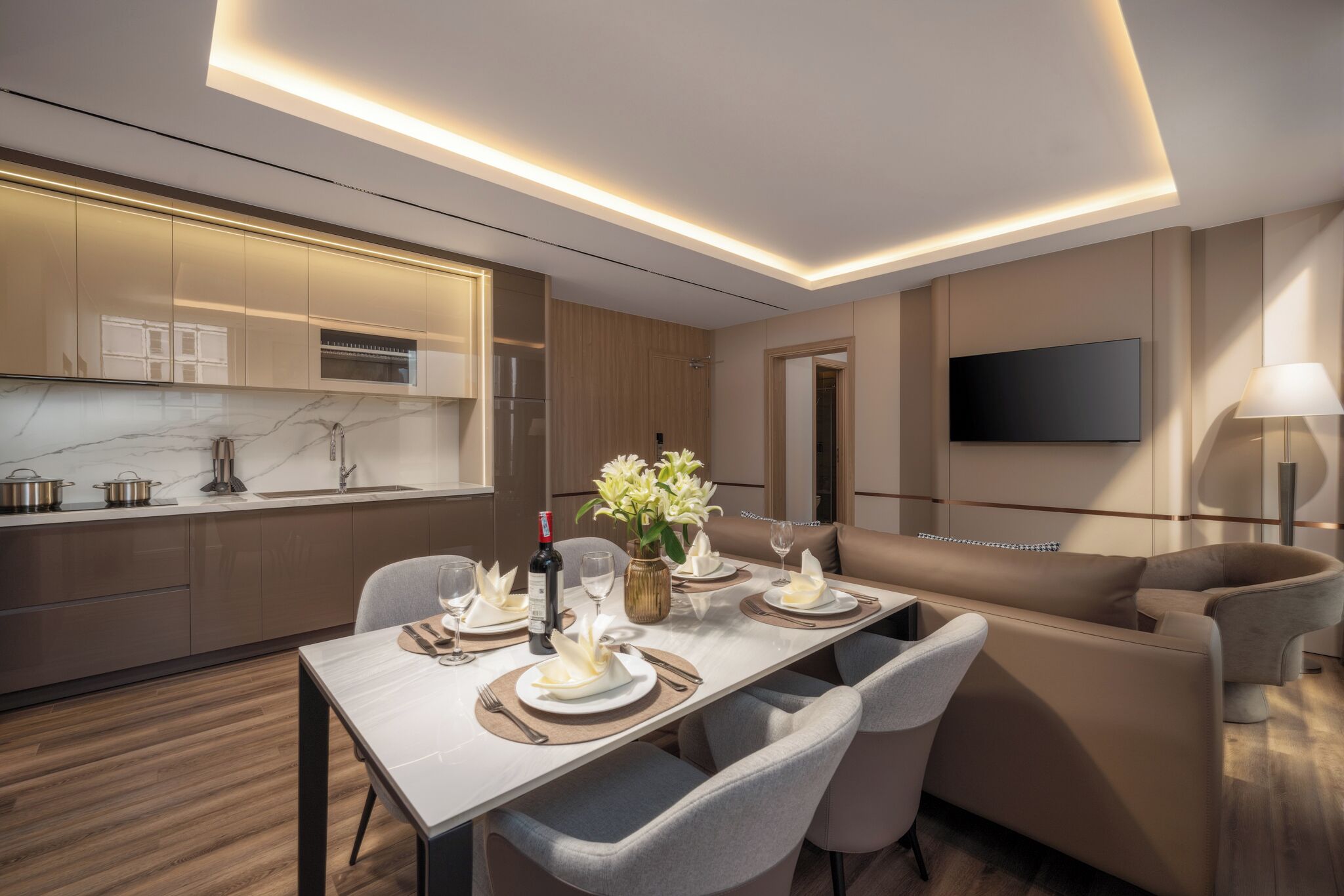 Una cocina moderna con electrodomésticos integrados, un comedor con mesa dispuesta para cuatro, y una zona de estar acogedora con sofá y sillones.