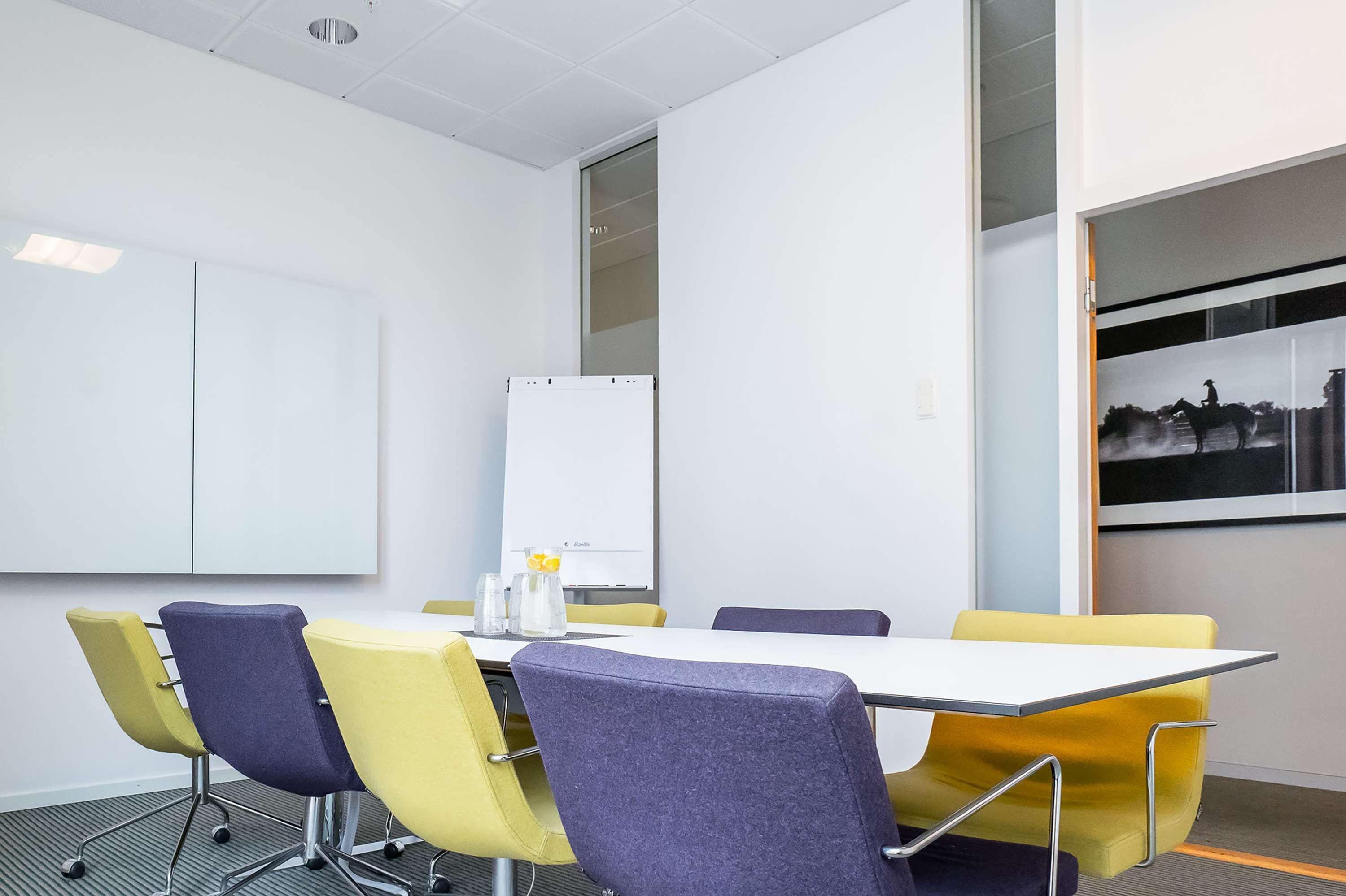 A conference room with a whiteboard, a table, and four chairs.