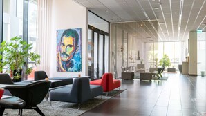 Een moderne lobby met een groot schilderij, zithoeken en uitzicht op het omliggende landschap.